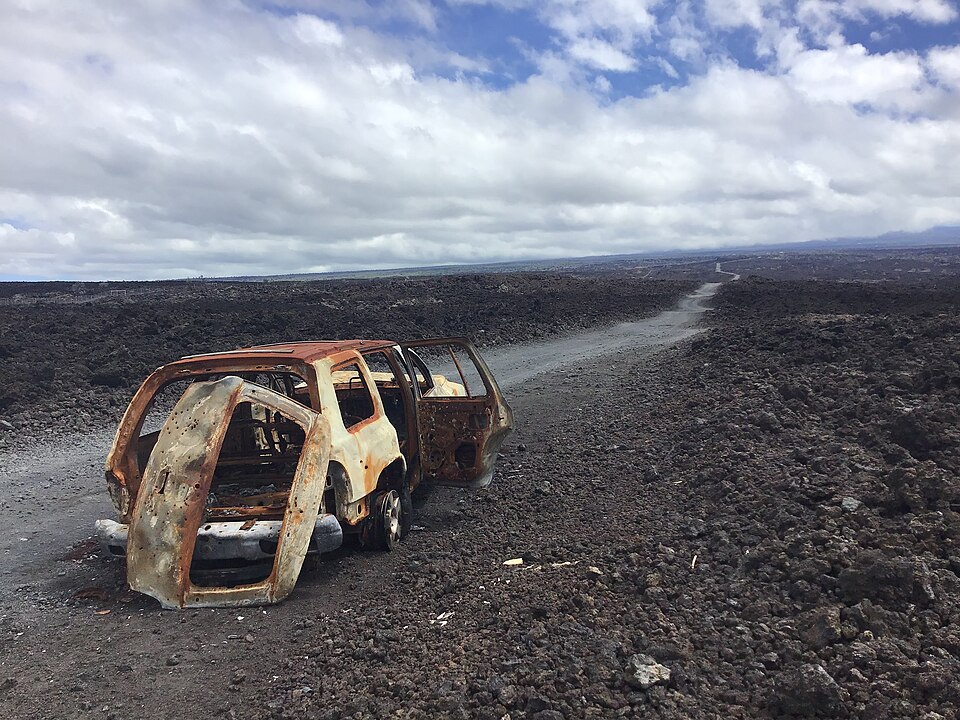 A burned vehicle beside a road crossing the lava fields of Hawaiian Ocean View Estates on Hawaiʻi Island.
