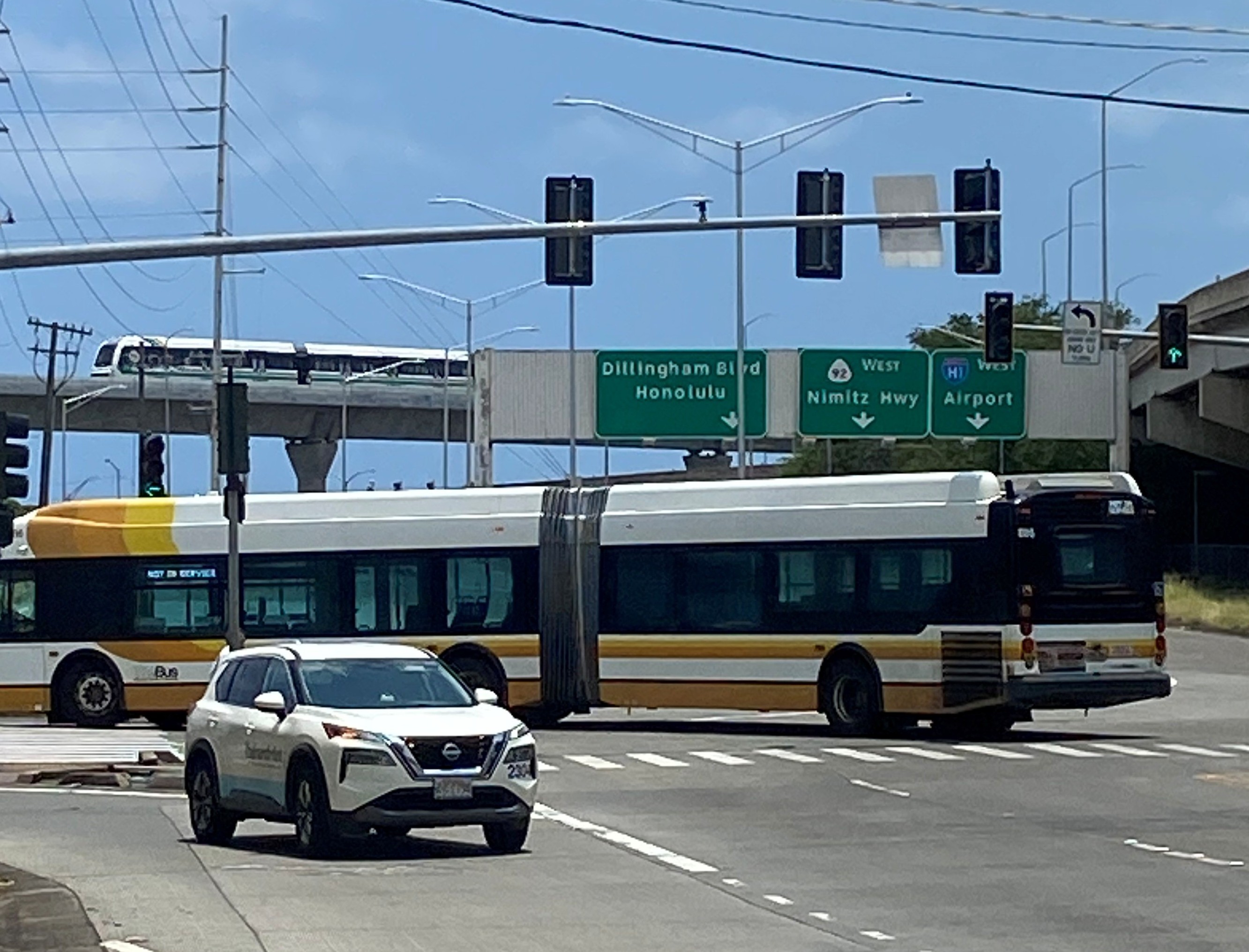 Middle Street in Honolulu with a city bus and Skyline train crossing the transportation corridor.
